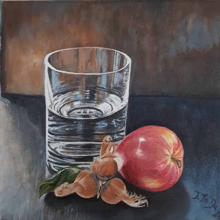 Wasserglas mit Haselnüssen und Apfel