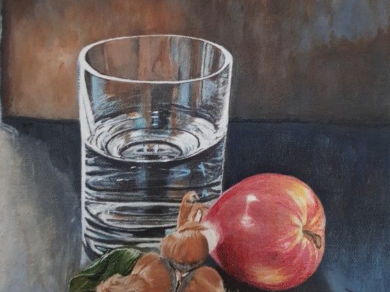 Wasserglas mit Haselnüssen und Apfel